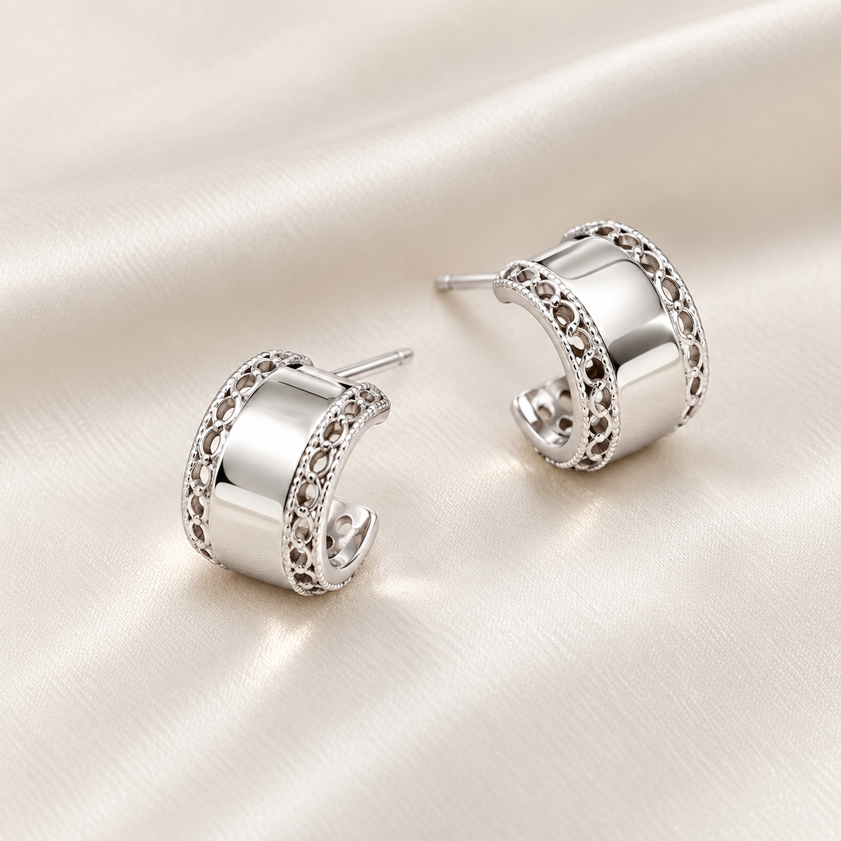 Digital product visualisation: silver carved wide stud earrings on ivory silk; macro view