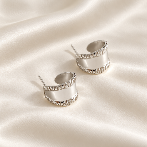 Digital product visualisation: silver carved wide stud earrings on ivory silk; overhead view