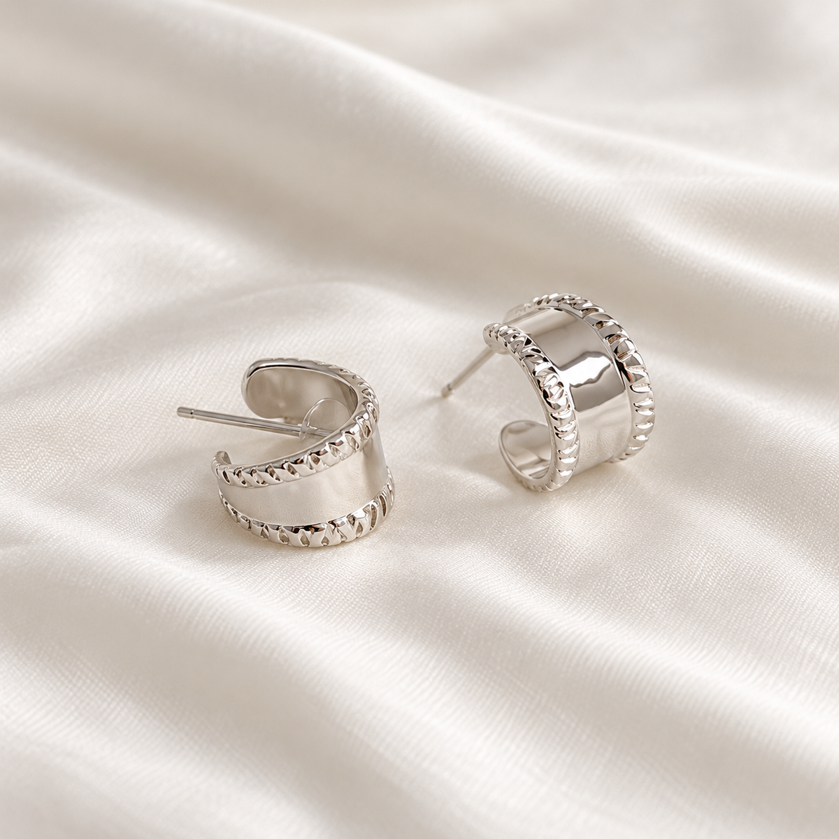 Digital product visualisation: silver carved wide stud earrings on ivory silk; rear view