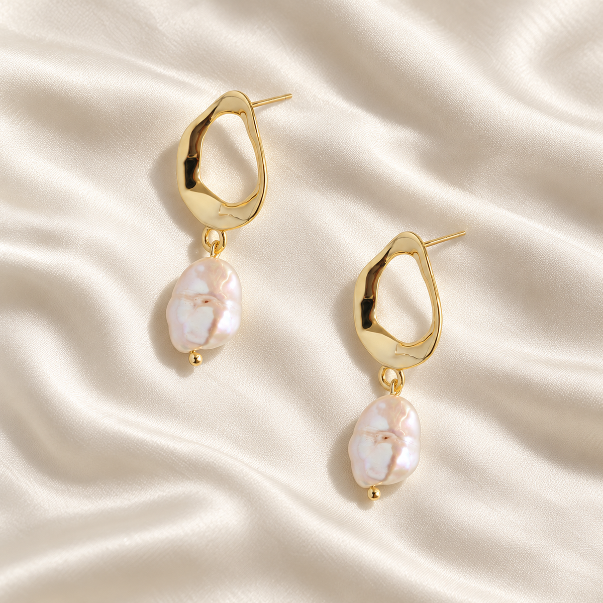 Digital product visualisation of pearl drop earrings in gold finish on ivory silk, overhead view