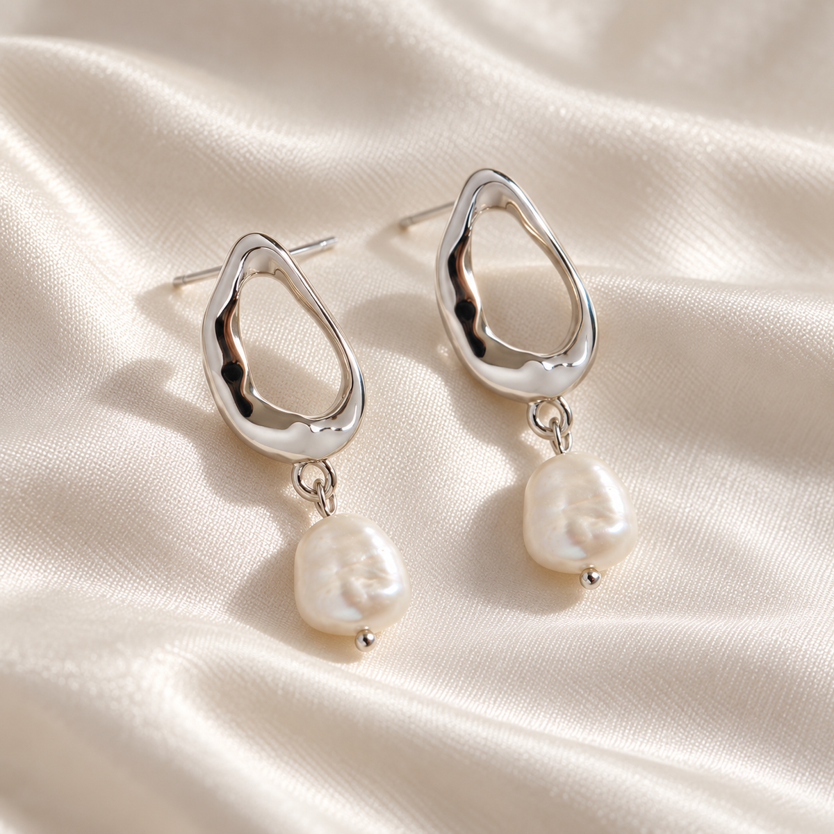 Digital product visualisation of pearl drop earrings in silver finish on ivory silk, macro view