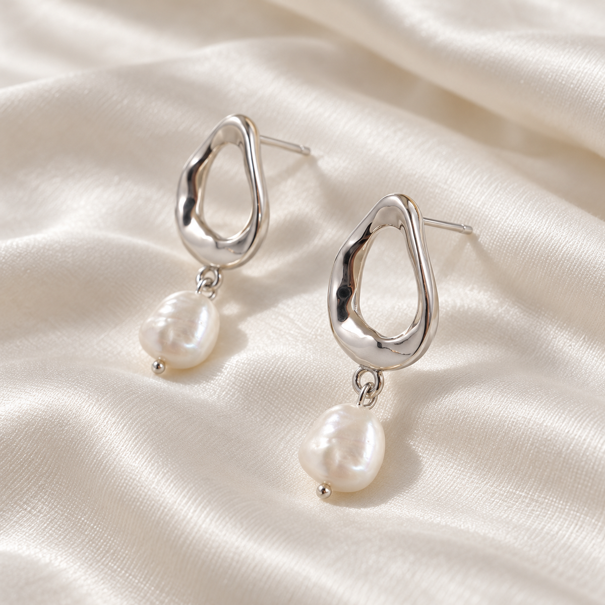 Digital product visualisation of pearl drop earrings in silver finish on ivory silk, side view