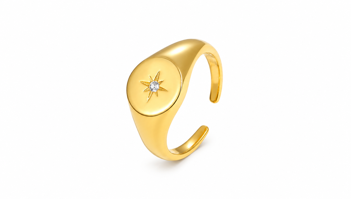 Gold sunburst signet ring on white studio background